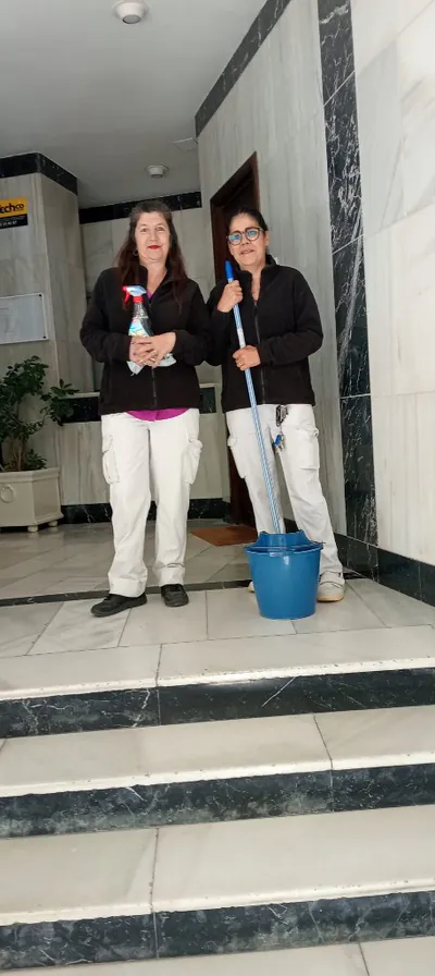 Dos operarias de Sara Rodríguez Limpieza, uniformadas, con equipo de limpieza en el portal de un edificio en Sevilla